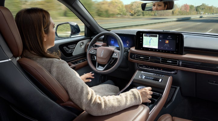 A 2026 Lincoln Aviator® SUV is being driven hands-free on a highway near a forest | Jenkins & Wynne Lincoln in Clarksville TN