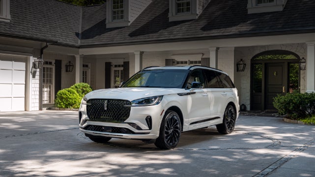 A white 2026 Lincoln Aviator® SUV is parked in the driveway of a luxury home. | Jenkins & Wynne Lincoln in Clarksville TN